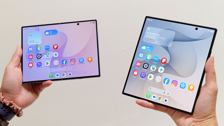 Samsung Galaxy Z Fold 8 ve Z Fold 8 Ultra beyaz bir duvar önünde açık halde tutuluyor