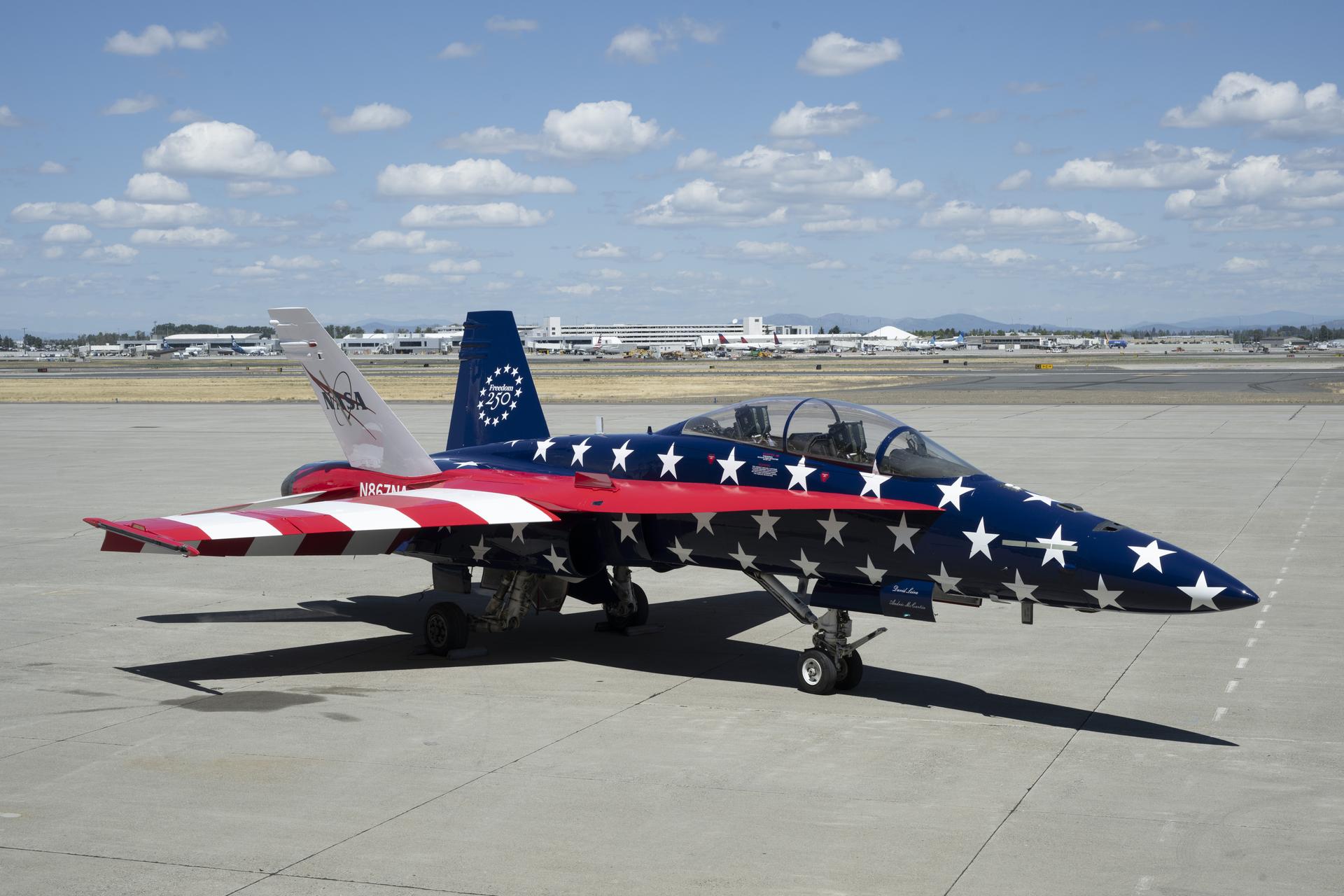 Two red, white and blue jet aircraft are sitting on the ramp ready for takeoff. The body of the aircraft is painted in blue with white stars, and the wings are red and white stripes to mirror the American flag.