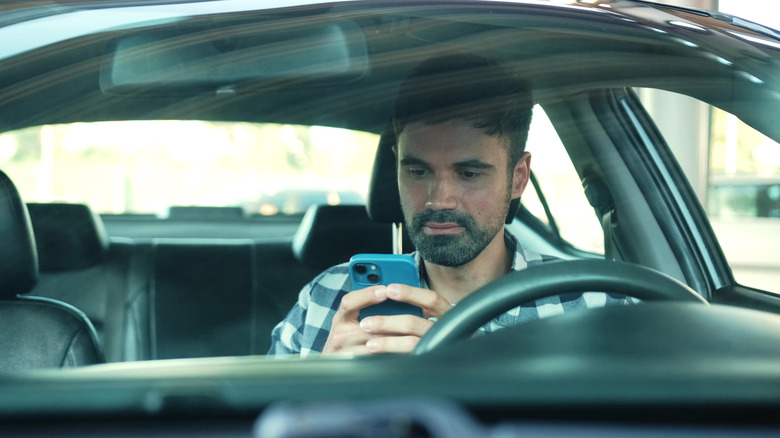 Arabada telefonunu kullanan bir adam