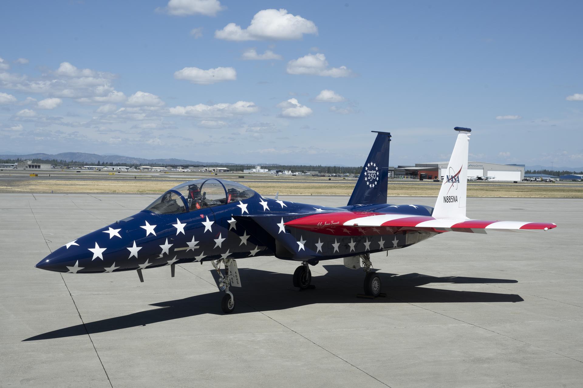 Two red, white and blue jet aircraft are sitting on the ramp ready for takeoff. The body of the aircraft is painted in blue with white stars, and the wings are red and white stripes to mirror the American flag.