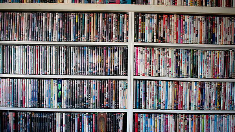 Bir rafta renkli bir Blu-ray ve DVD yığını görülüyor.