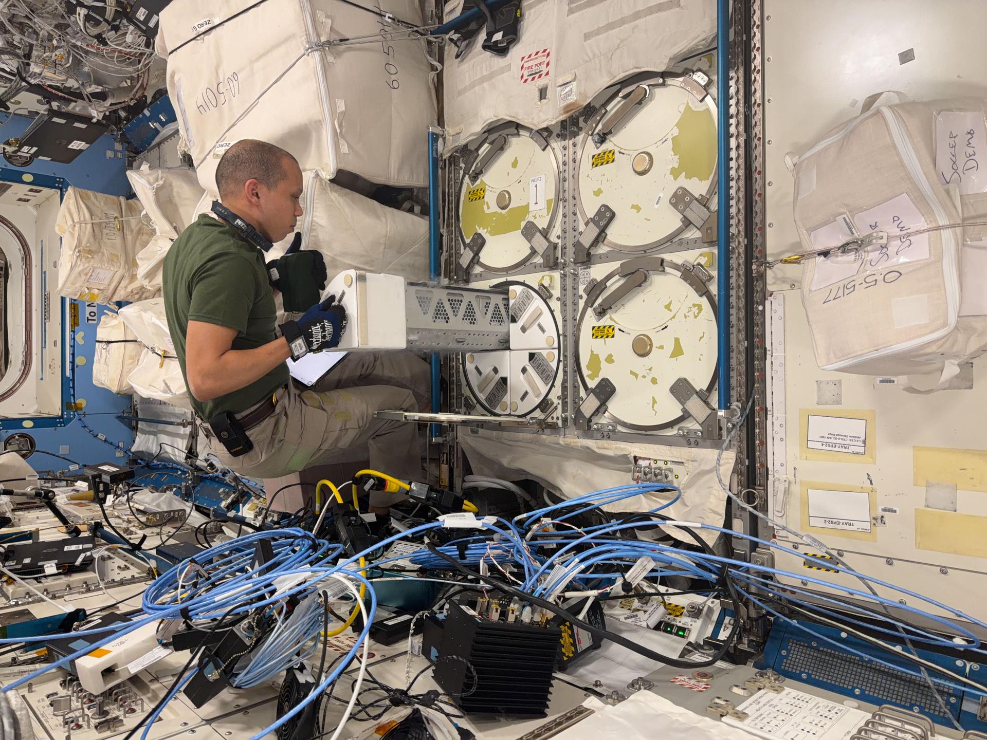 NASA astronaut Chris Williams works with science freezer