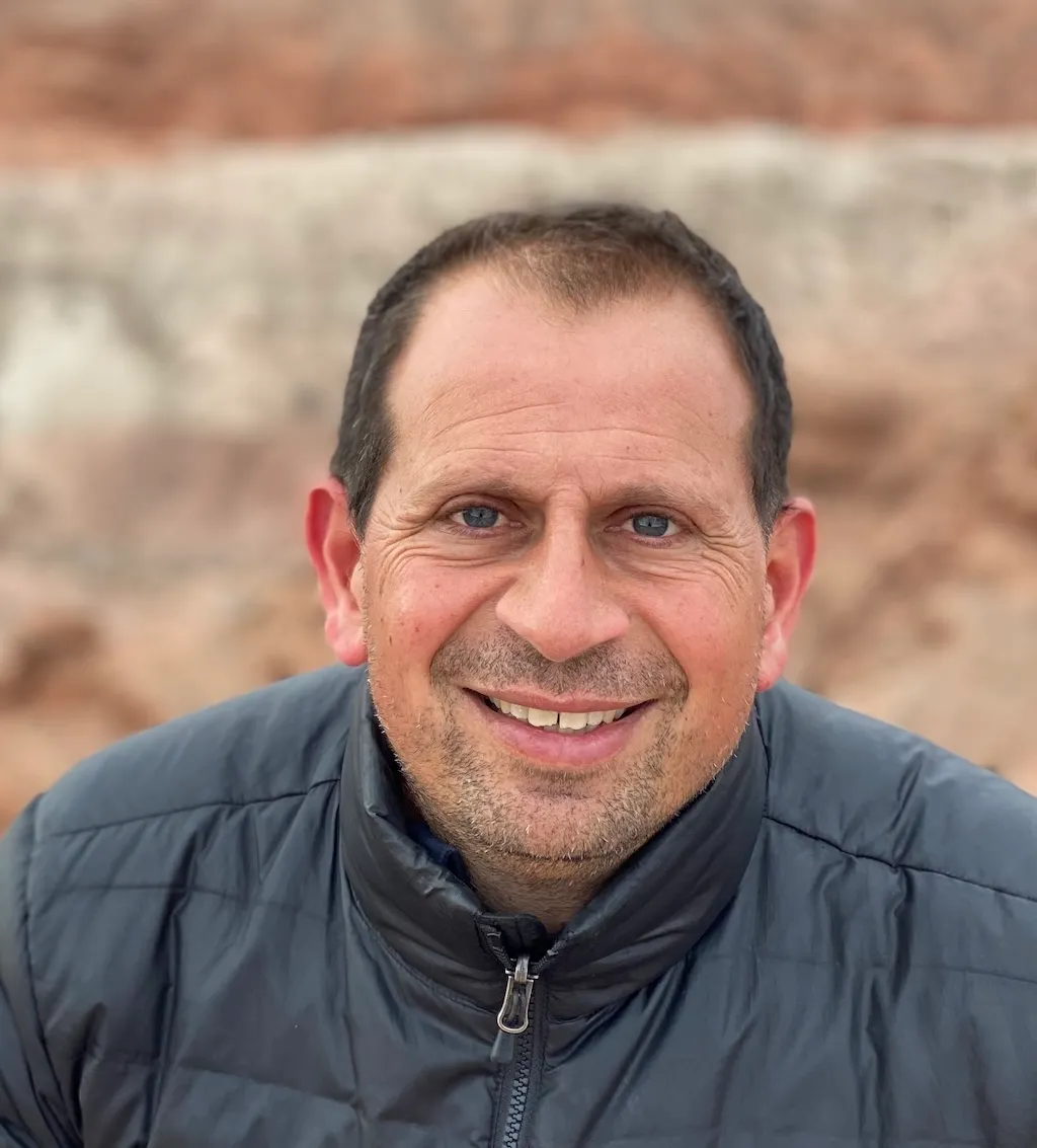 Eduardo Bendek with brown hair and a grey zip up jacket