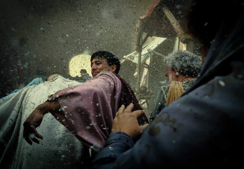 A Pompeii civilian battles his way through the crush of people rushing to evacuate the city of Pompeii as ash falls from the sky.