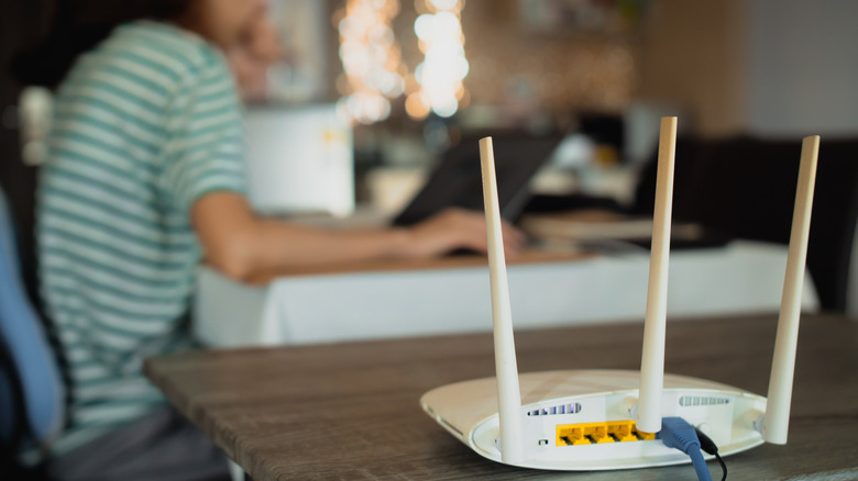 Evden çalışan bir kadın ve yanındaki masada beyaz bir router