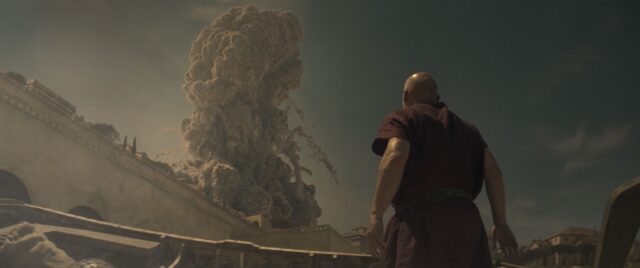 The Praetorian (Barry Aird) stands on the beach looking up in horror as the eruption column from Vesuvius towers into the sky over the city walls of Herculaneum.